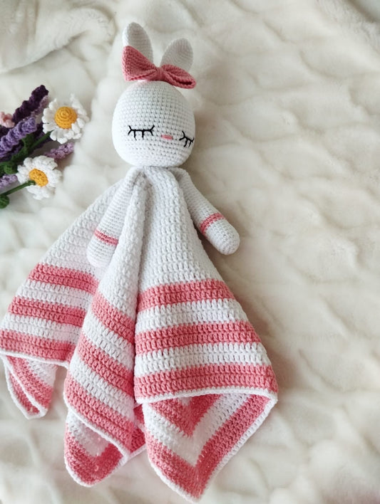 Crocheted bunny lovey with pink and white stripes, closed eyes, and a bow