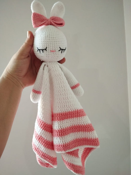 Crocheted bunny lovey with pink and white stripes, closed eyes, and a bow