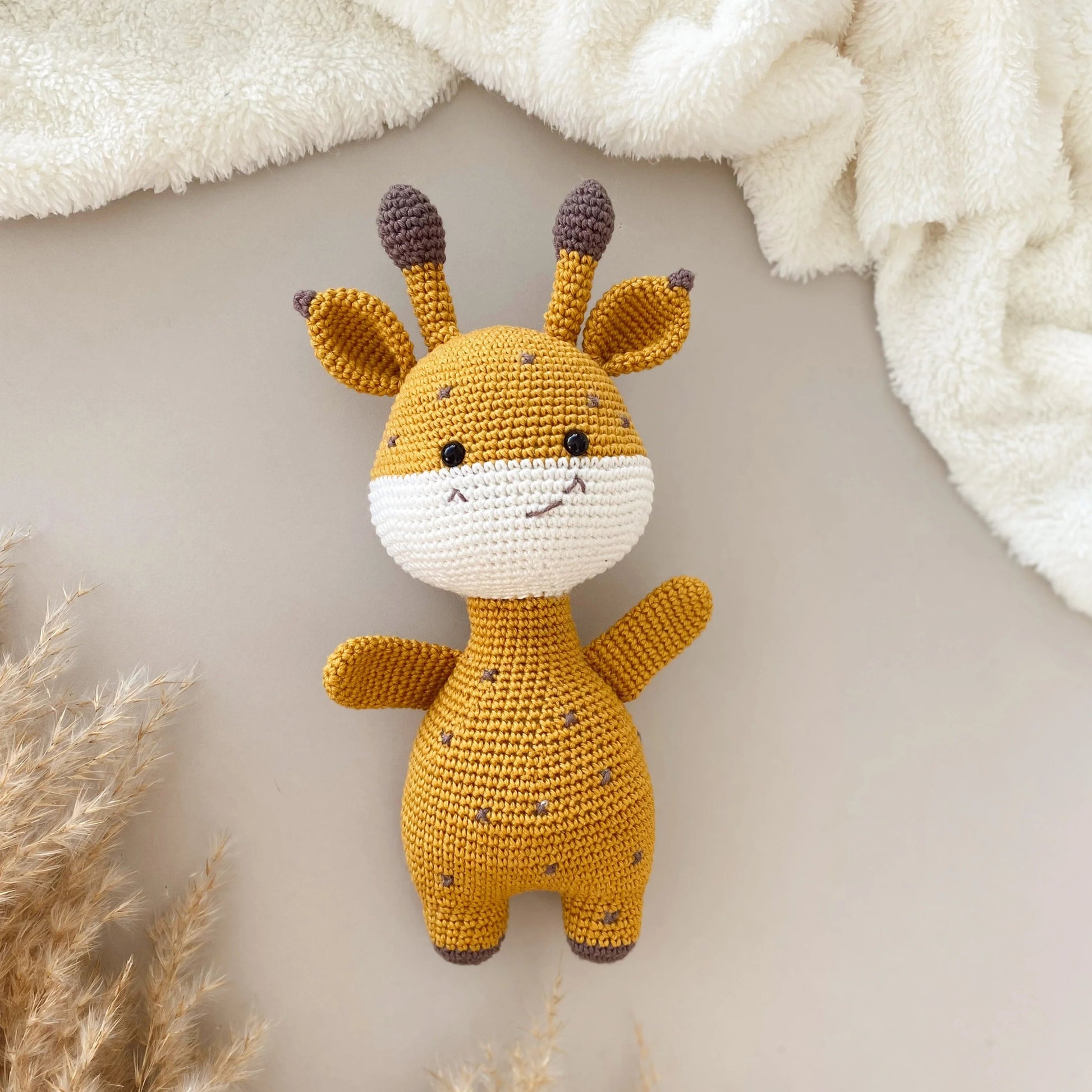 Crocheted yellow and white giraffe plush toy with cute smiling face and brown-tipped ears