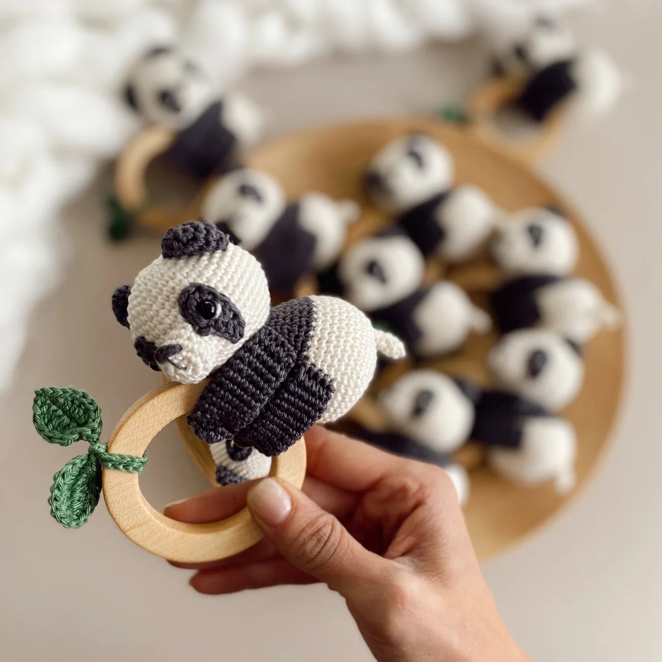 Crocheted panda baby rattle with wooden teething ring and green leaf detail