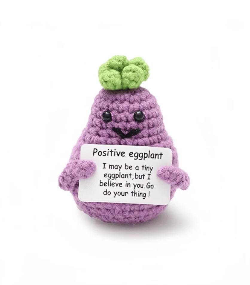 Crocheted purple eggplant with cute face, holding motivational encouragement sign