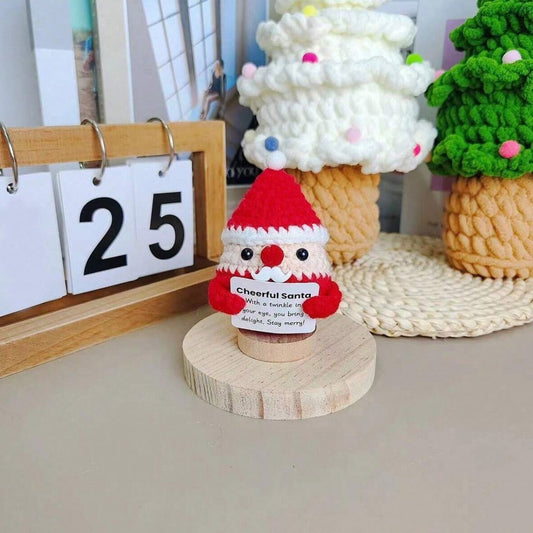 Crocheted Santa figurine with a cheerful message on wooden stand, calendar shows 25