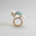 Crocheted turtle rattle on wooden teething ring with soft blue and cream colors