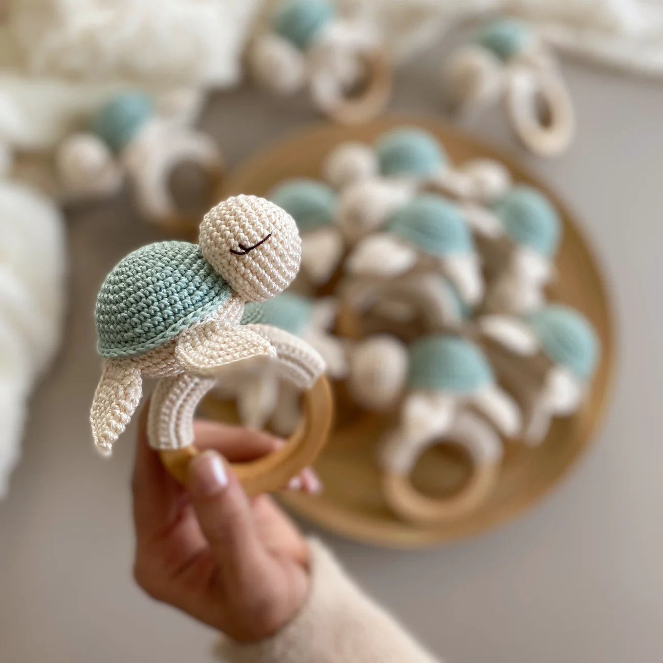 Crocheted turtle rattle on wooden teething ring with soft blue and cream colors