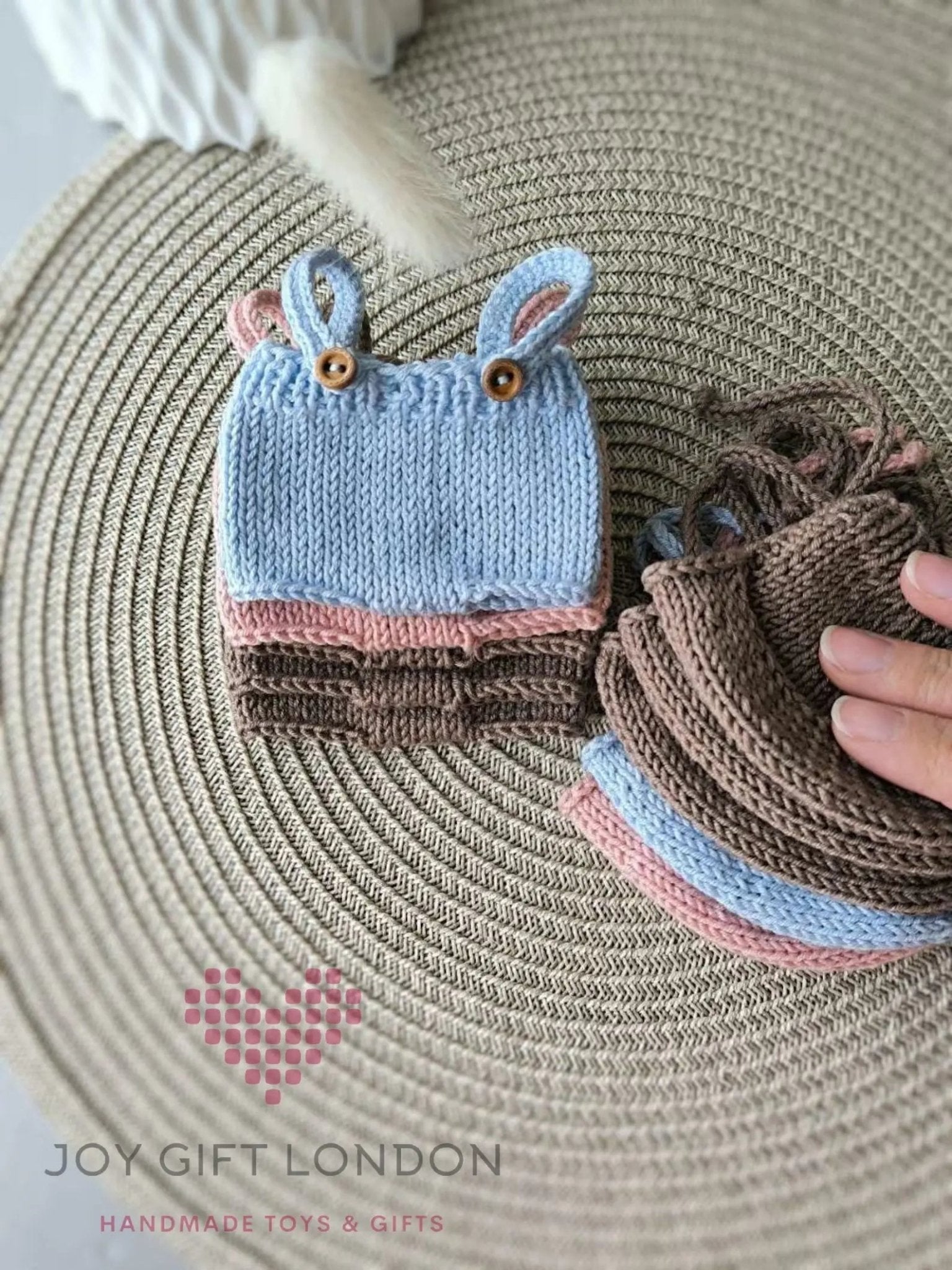 Blue knitted baby hat with bunny ears and wooden buttons on textured background
