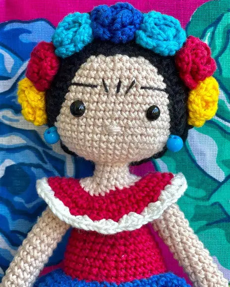 a crocheted doll sitting on top of a pillow