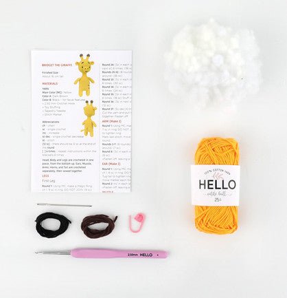 Crochet giraffe kit with yellow yarn, pattern, crochet hook, and black and pink accessories