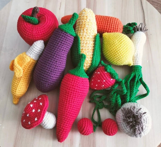 Crocheted fruits and vegetables in vibrant colors arranged on a wooden surface