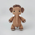 Crocheted toy mammoth named Peanut on a wooden surface with yarn and patterns displayed.