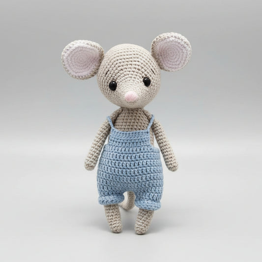 Crocheted mouse toy in blue overalls, standing against a neutral background