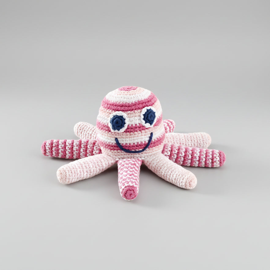Crocheted pink and white octopus toy with a smiling face and blue eyes