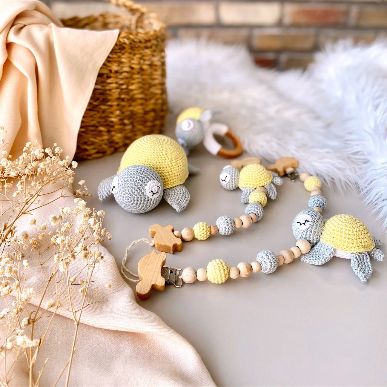 Crocheted yellow and gray turtle toys with wooden teething accessories on soft blanket
