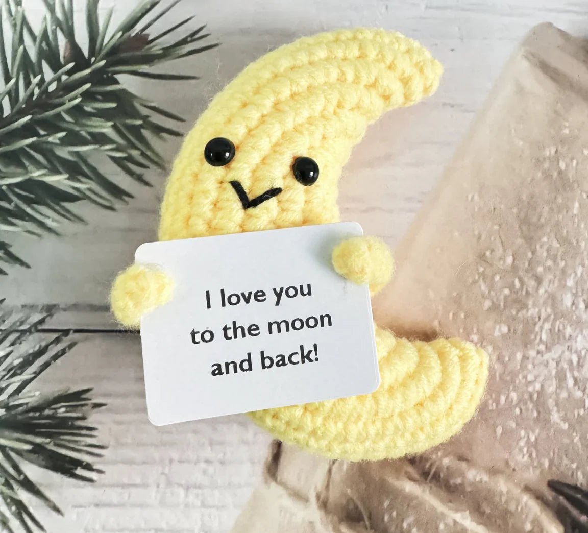 Yellow crocheted banana holding a note that says "I love you to the moon and back!"