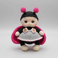 Crocheted ladybug doll with pink antennae and cute gray dress on gray background