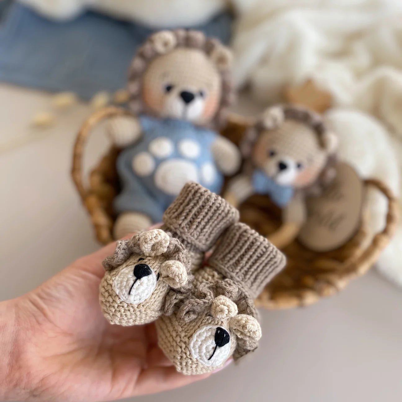Crocheted baby booties shaped like teddy bears, with stuffed bear toys in background