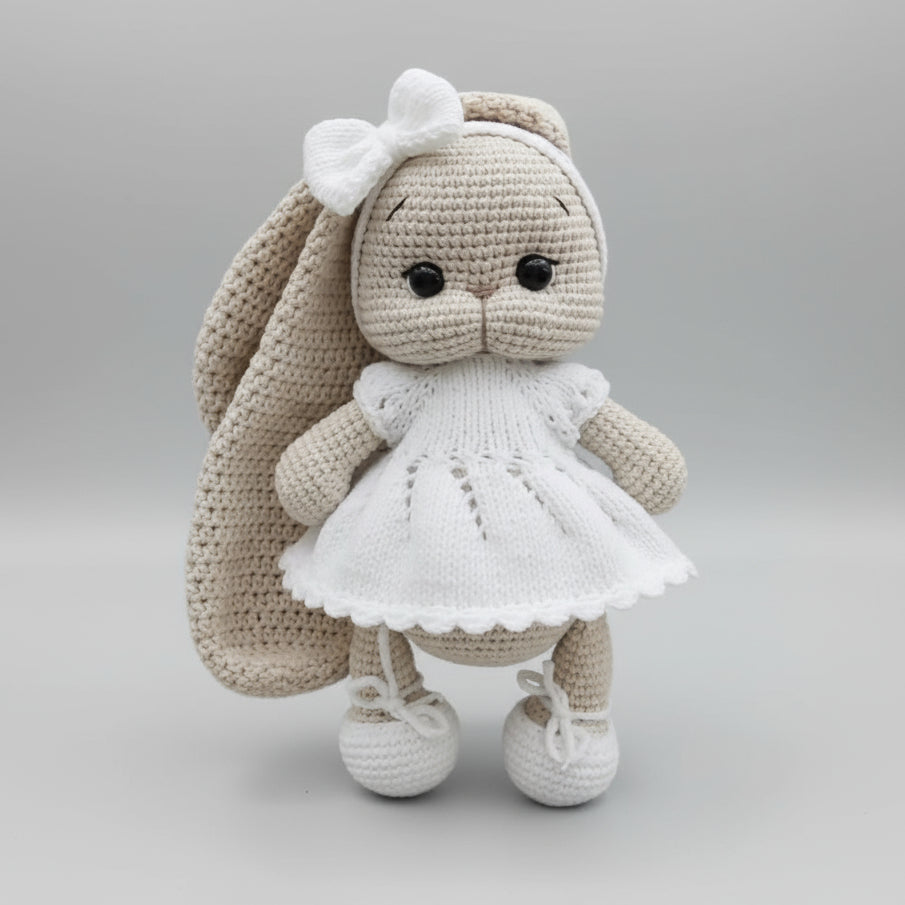 Crocheted bunny doll in white dress with bow, wearing tiny white shoes