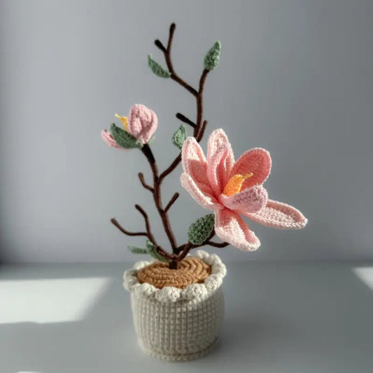 Delicate crocheted pink blossom with brown branch in white knitted pot