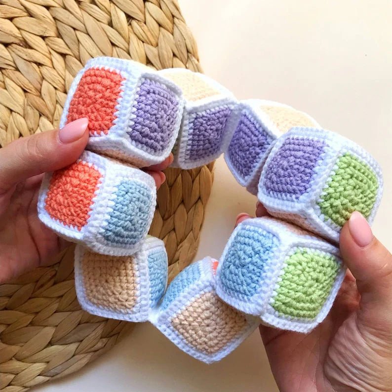 Colorful crocheted soft cubes with textured yarn sections in pastel colors