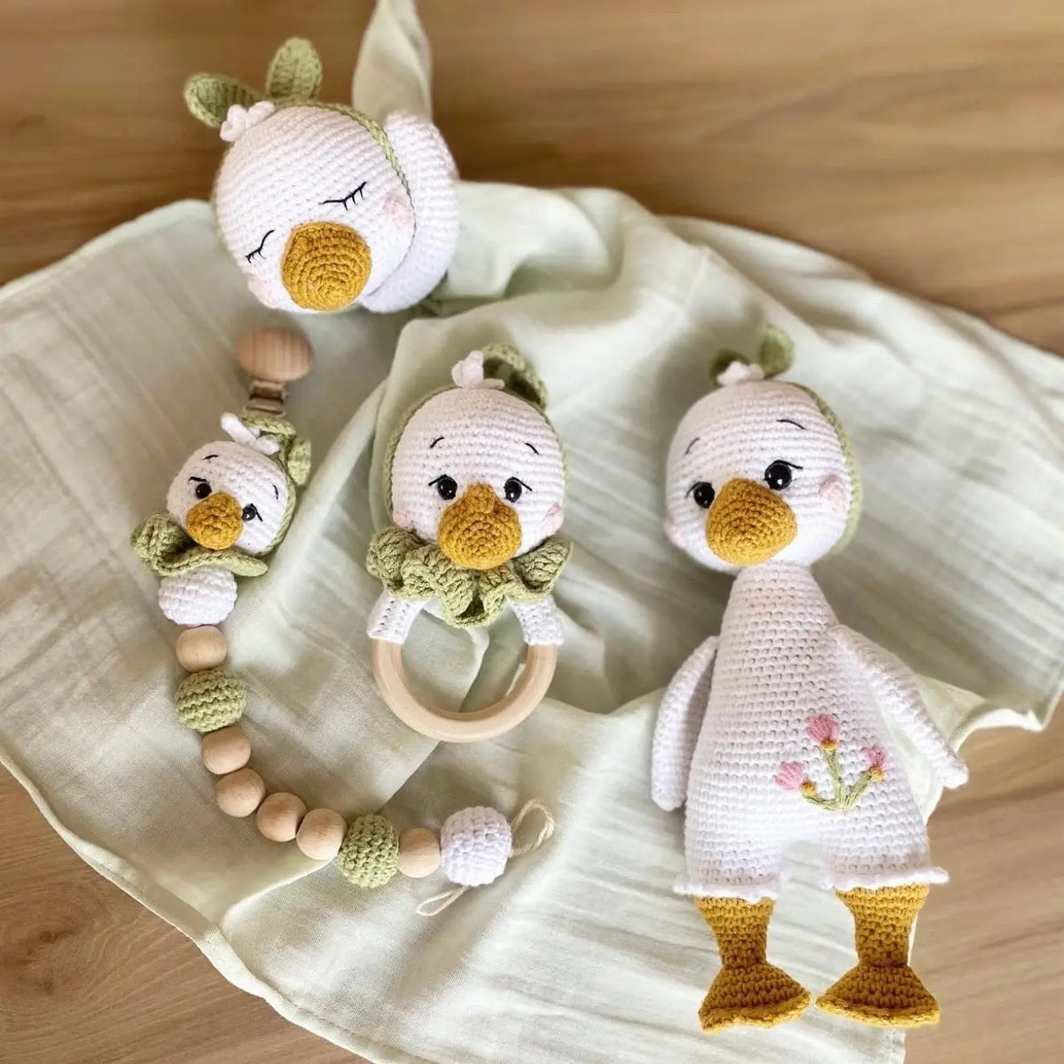 Crocheted baby set with three cute duck toys and wooden teething ring on cloth