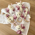 Crocheted butterfly-shaped baby toys in cream and pink, with wooden teething ring