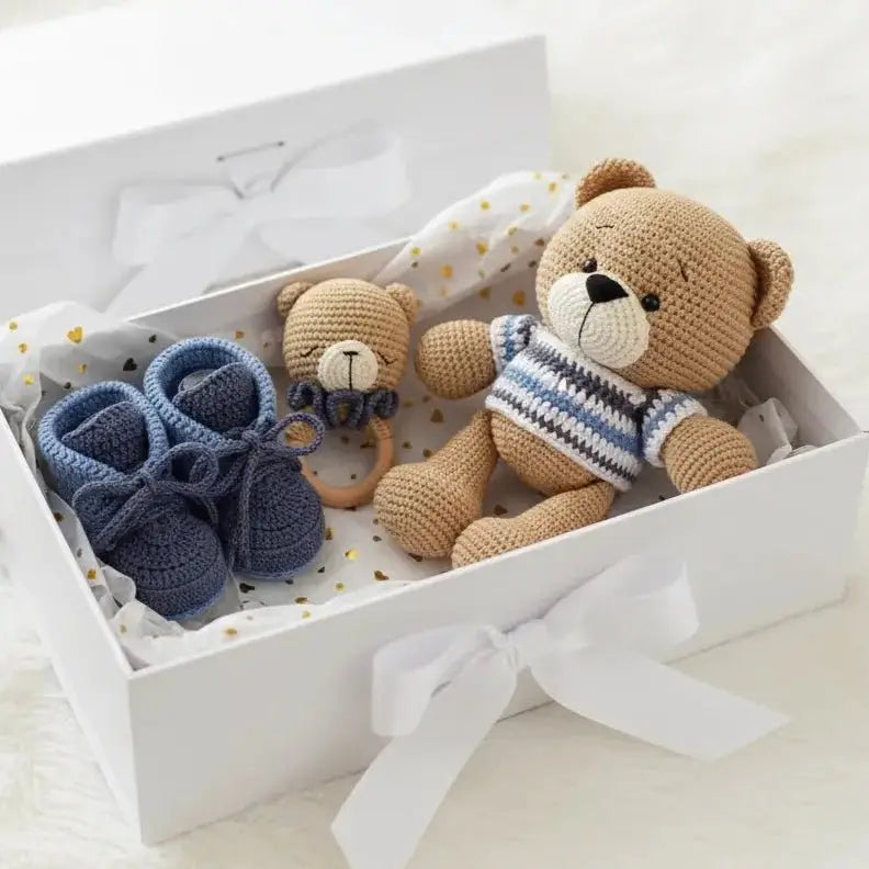 Crocheted teddy bear and blue booties in a white gift box with gold-dotted lining