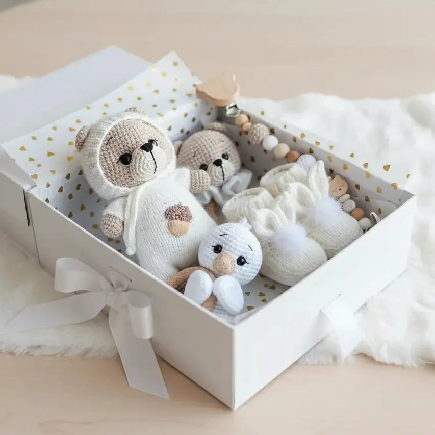 Crocheted stuffed animals nestled in a white gift box with gold hearts and ribbon