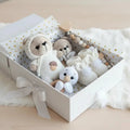 Crocheted stuffed animals nestled in a white gift box with gold hearts and ribbon