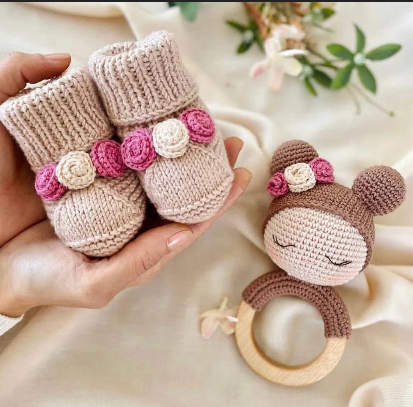 Knitted baby booties and crochet bear teething ring with pink floral details