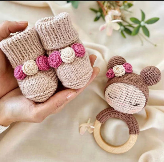 Knitted baby booties and crochet bear teething ring with pink floral details