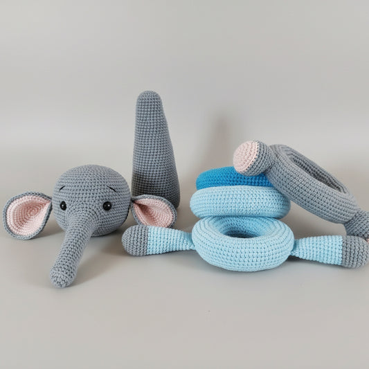 Crocheted gray and blue elephant toy with stacking rings on wooden surface