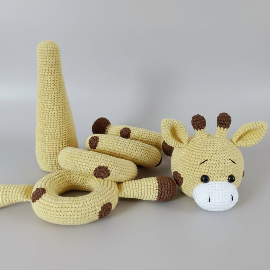 Crocheted yellow giraffe toy with brown spots, lying on wooden surface