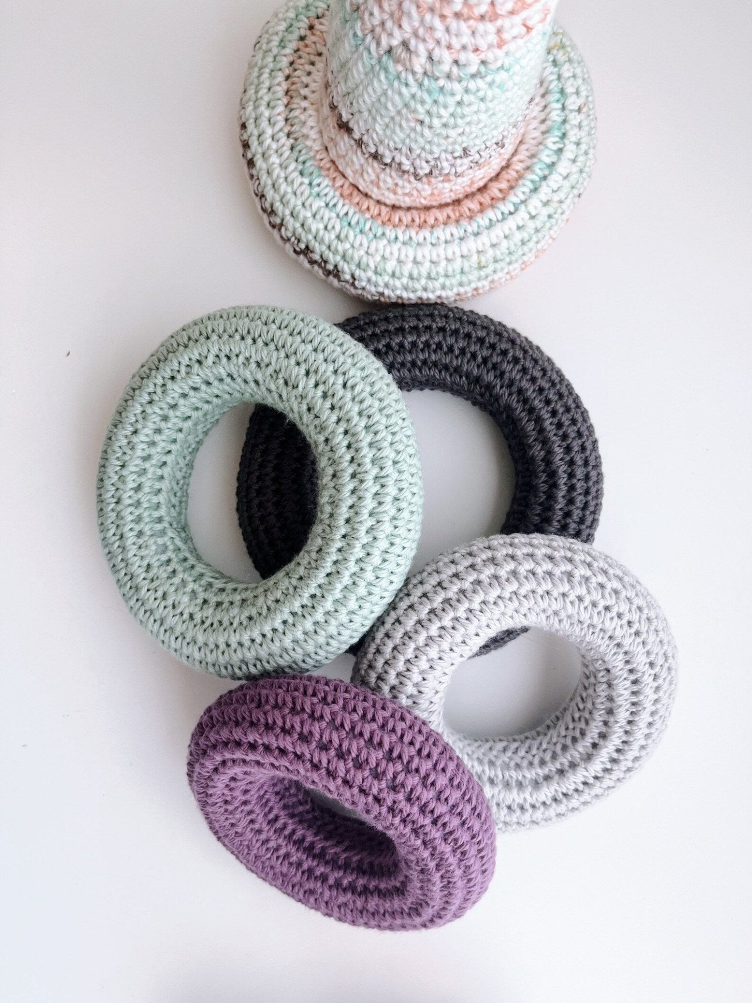 Crocheted rings in pastel colors: mint green, gray, white, purple, and soft peach