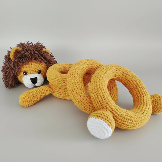 Yellow crocheted lion and rings on wooden surface, handmade amigurumi toys
