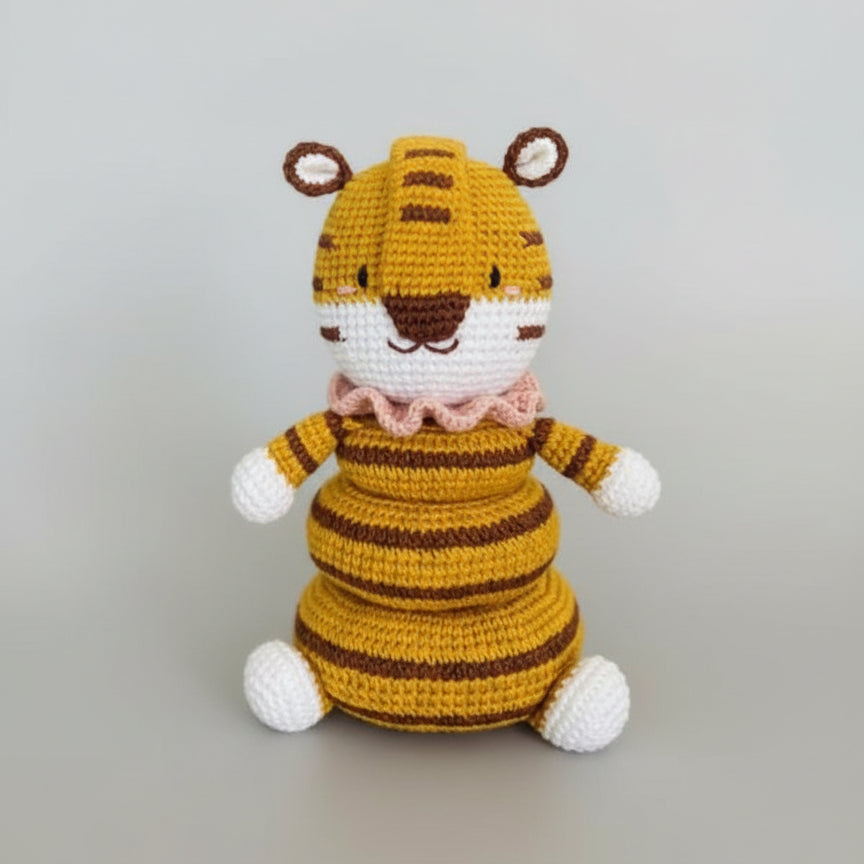 Crocheted tiger stuffed animal in yellow and brown stripes with white paws