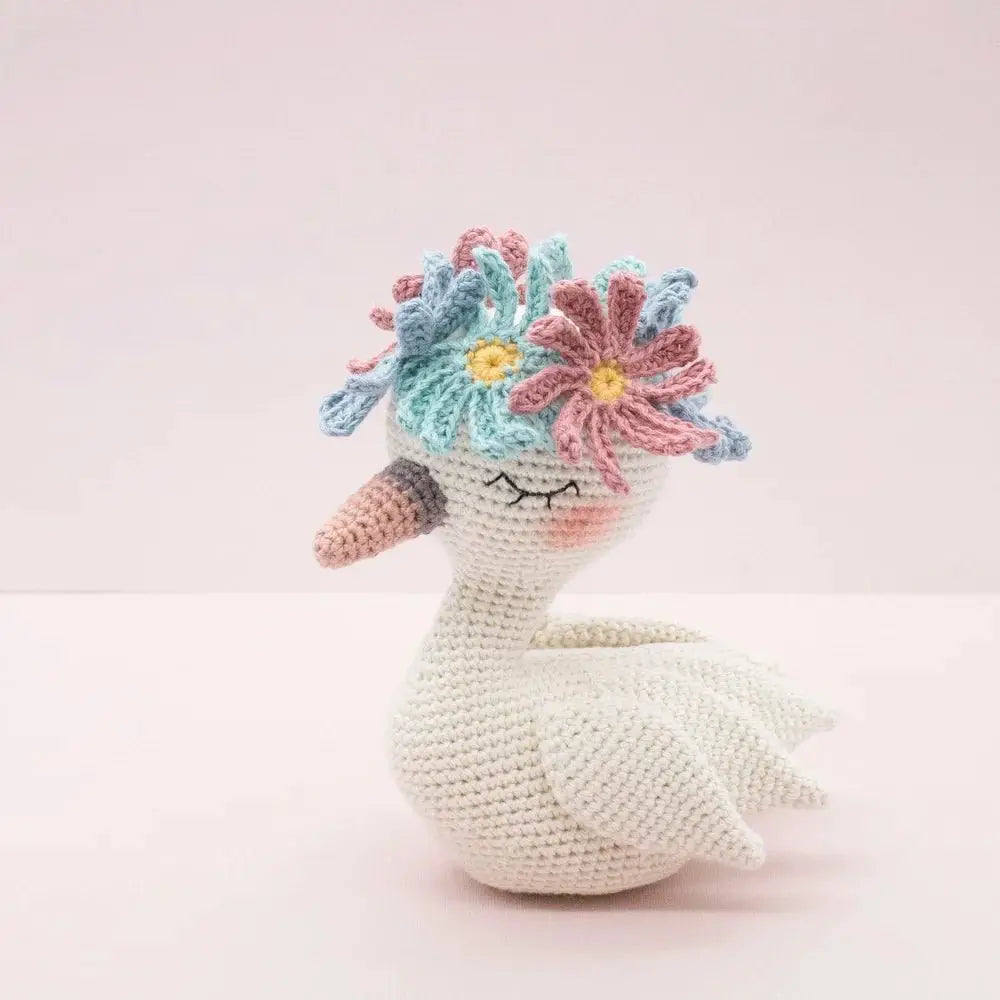 Crocheted white swan with colorful flower crown, soft pastel colors and whimsical design