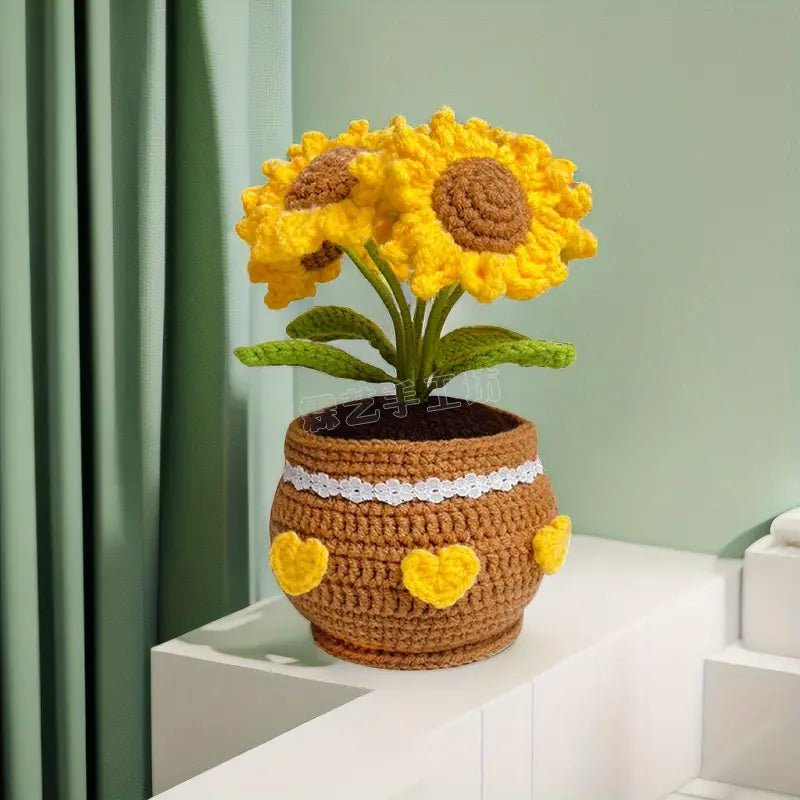 Crocheted sunflowers in a brown yarn pot with heart decorations, placed on white surface