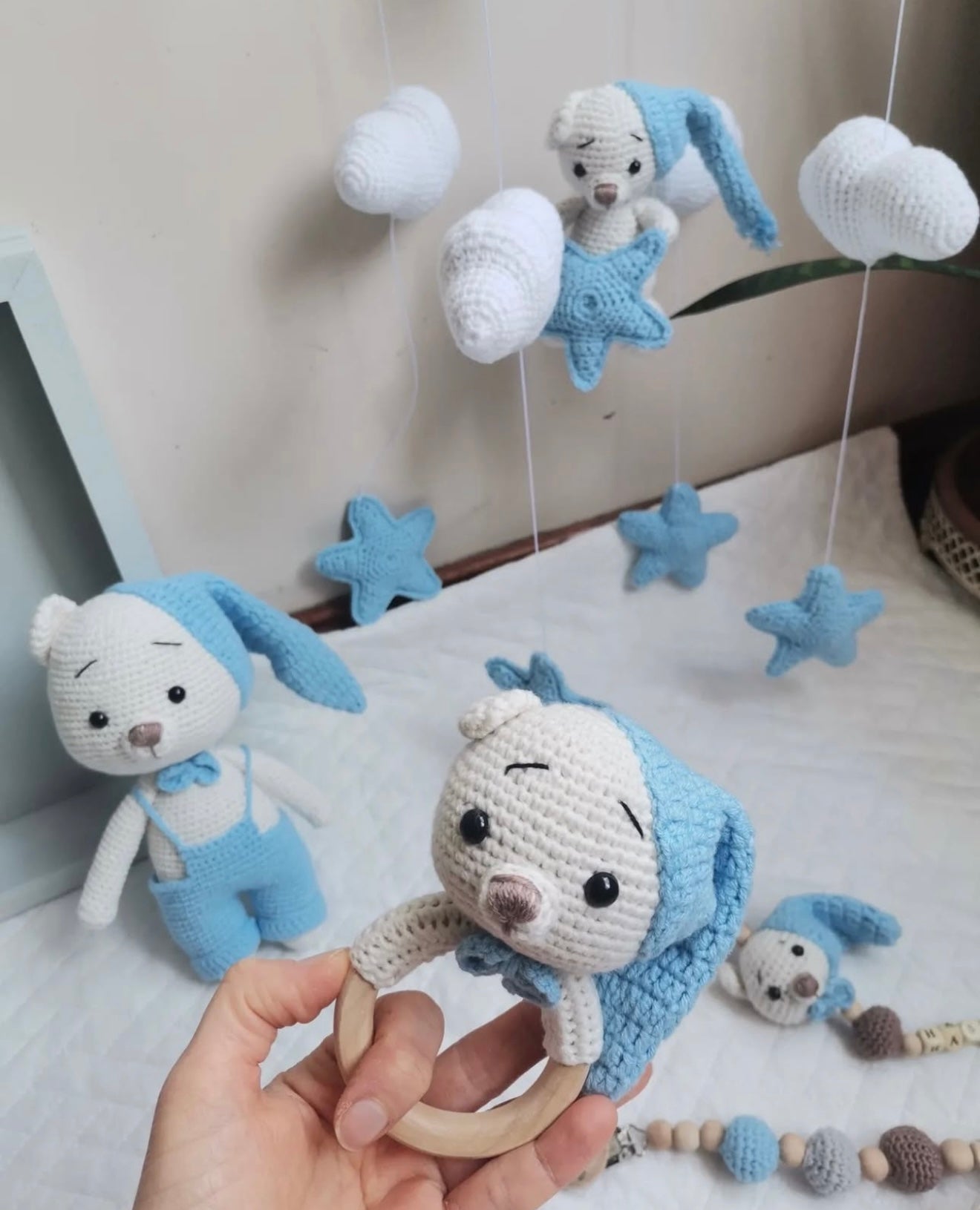 Crocheted blue and white baby toys: stuffed bears, stars, clouds on wooden teething ring