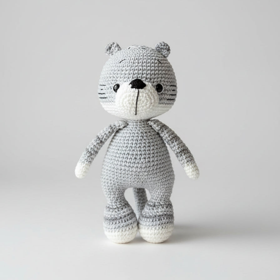 Gray and white crocheted teddy bear with button eyes standing upright