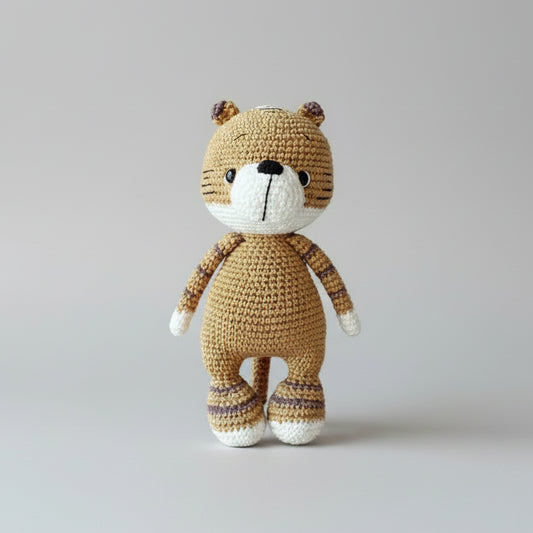 Crocheted teddy bear in tan and white, standing on a gray background