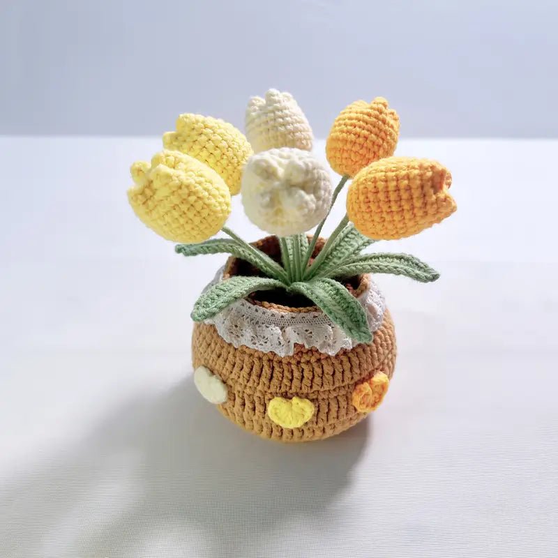 Crocheted tulips in yellow, white, and orange nestled in a textured yarn pot