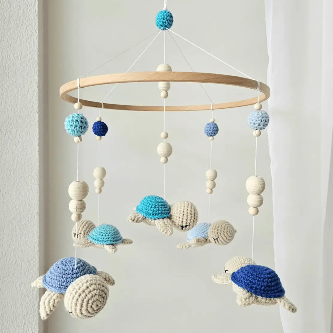 Crocheted turtle baby mobile in blue, white, and navy hanging from wooden ring