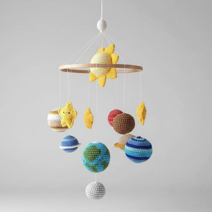 Crocheted mobile with colorful balls and fish hanging against a neutral wall.