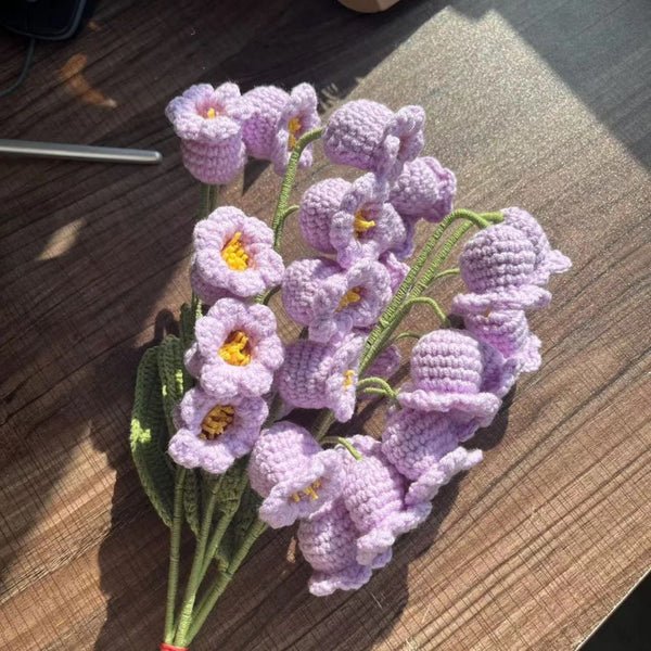 Crocheted lavender flowers with yellow centers on wooden surface