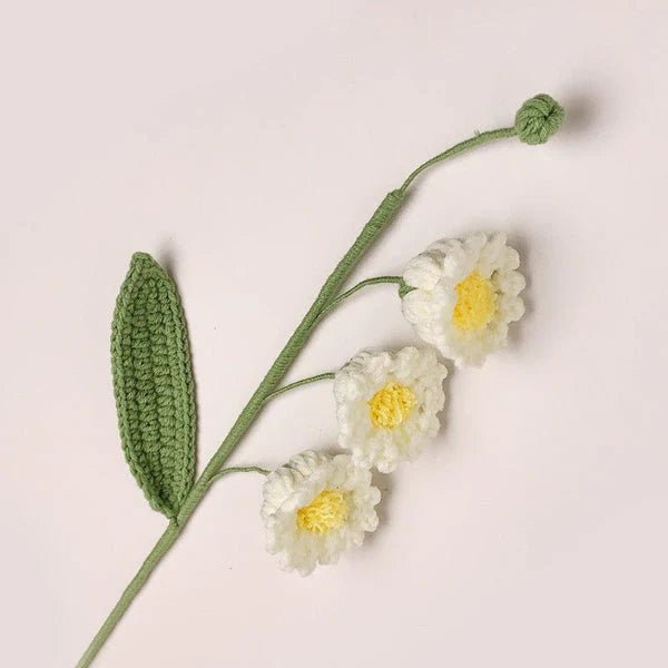 Crocheted white daisies with yellow centers on green stem with leaf