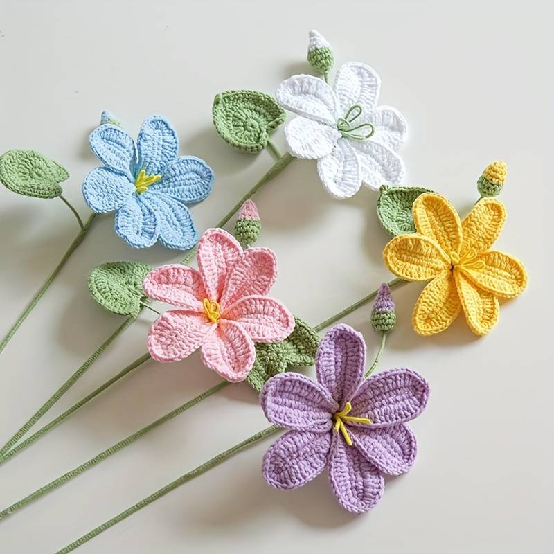 Colorful crocheted flowers in pastel blue, pink, white, yellow, and purple with green stems
