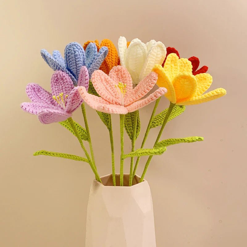 Colorful crocheted flowers in various pastel hues arranged in a white ceramic vase