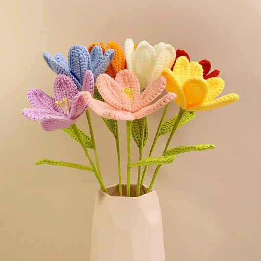 Colorful crocheted flowers in various pastel hues arranged in a white ceramic vase