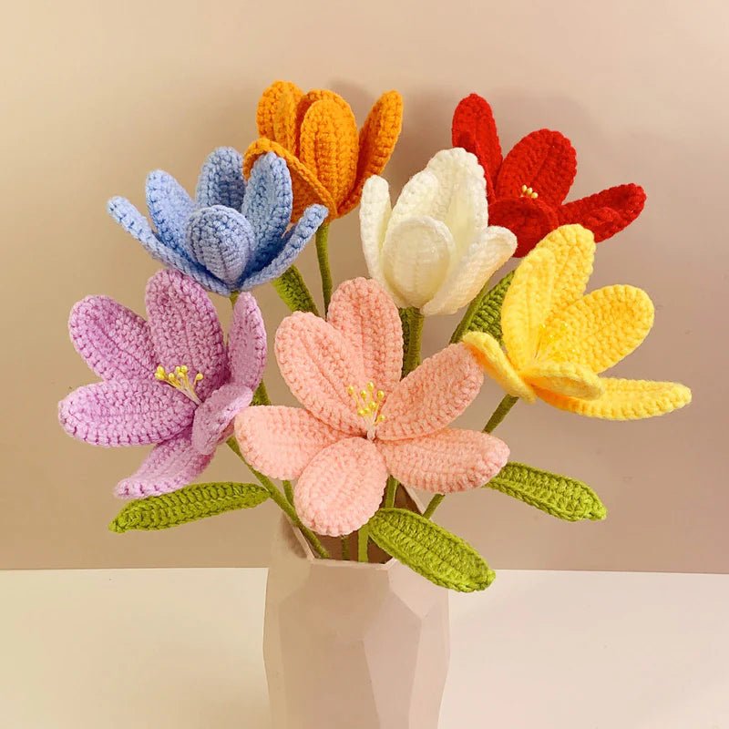 Colorful crocheted tulips in rainbow hues arranged in a white ceramic vase