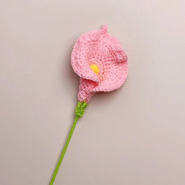 Pink crocheted calla lily with green stem against neutral background