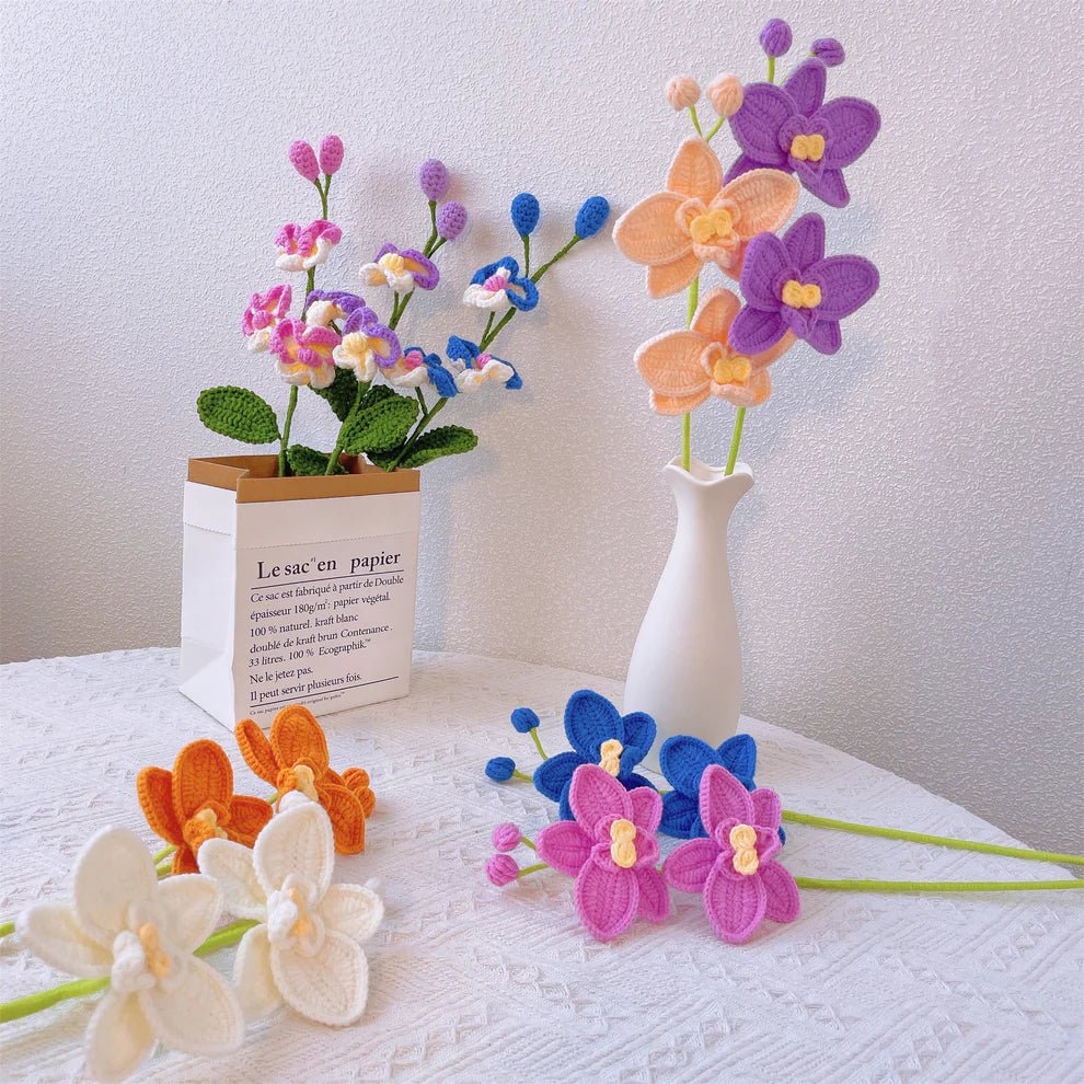 Colorful crocheted orchids in white vase and paper bag on lace tablecloth
